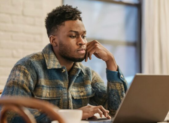 serious black man working on laptop in workspace