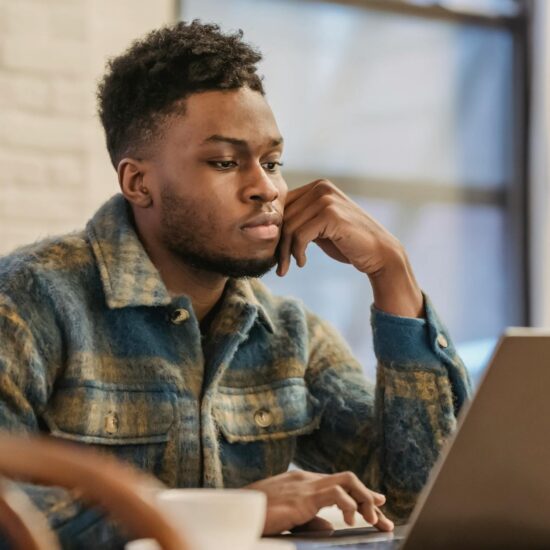 serious black man working on laptop in workspace