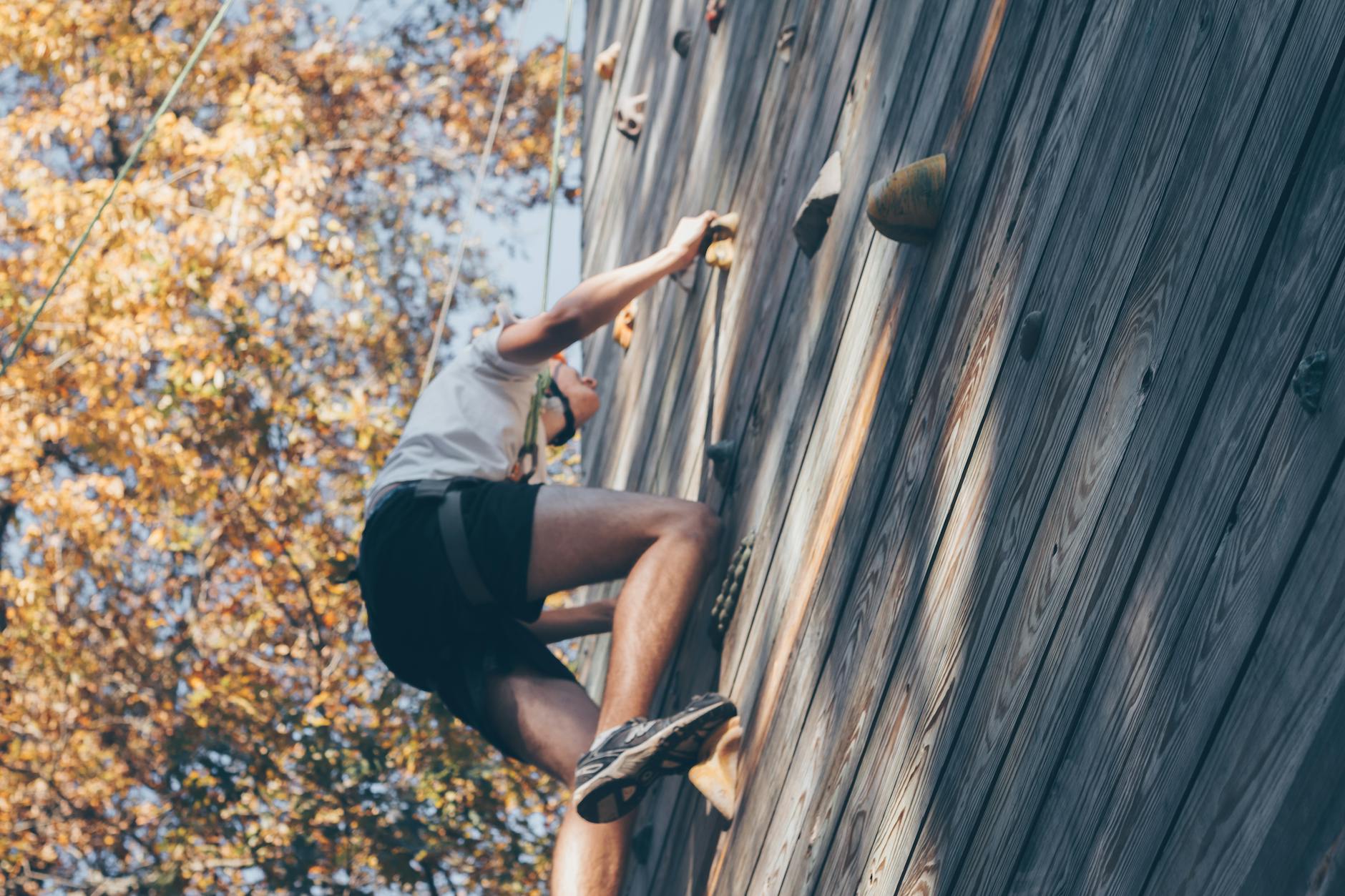 man wall climbing beside trees